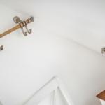 Wandhalterung mit Haken und Schreibtischlampe neben einem Bett.