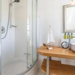 Dusche mit Glaswand, Waschtisch mit Holzplatte und Spiegel