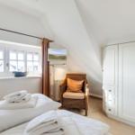 Schlafzimmer mit Dachschrägen, Bett, Schrank und Sessel.