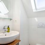 Badezimmer mit Waschbecken, Spiegel und Dachfenster
