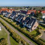 Aerial view of a residential area with houses, gardens, and a paved path.