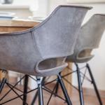 Zwei graue Sitzhocker mit schwarzen Metallbeinen stehen an einem Holztisch.