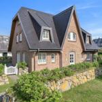 Two-story house with stone wall and white windows