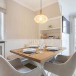 Dining room with wooden table, chairs, and windows. Ceiling light and TV visible.