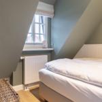 Bedroom with sloped ceilings, window, bed, and radiator.