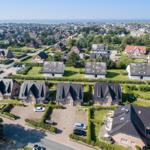 Aerial view of residential area with houses and greenery near the sea.