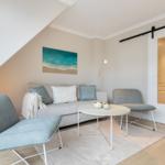 Living room with sofa, two chairs, and round table under sloped ceiling.