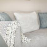 A sofa with cushions and a fringe blanket.