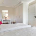 Schlafzimmer mit Bett, Kleiderschrank und Sessel.