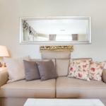 Ein Sofa mit Kissen, Spiegel und Beistelltisch im Wohnzimmer.