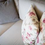 Ein Sofa mit zwei floralen Kissen und zwei grauen Kissen.