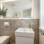 Bathroom with sink, mirror, and toilet. Wall with stone tiles.