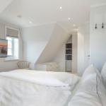Bedroom with sloped ceiling, bed, TV, and coat rack.