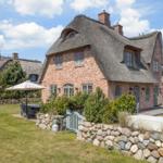House with thatched roof and stone wall in the garden.