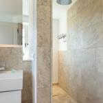 Bathroom with stone wall, shower, and sink with mirror