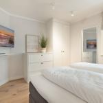 Bedroom with double bed, wardrobe, and TV mounted on the wall.