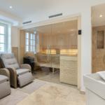Sauna with glass wall, shower, and hot tub in one room.