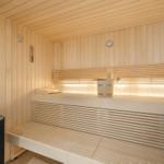 Sauna with wooden benches, thermometer, and wooden bucket