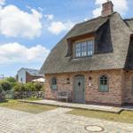 House with thatched roof and brick facade. Gray door and windows.