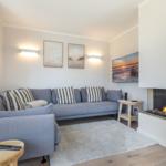A living room with gray sofa, fireplace, and wall art.