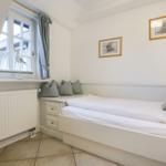 Bedroom with white bed, window, and wall pictures