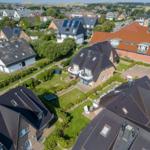 Aerial view of residential houses with gardens and roofs in a town setting.