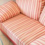 A sofa with striped upholstery in red-beige tones.