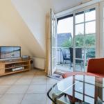 Living room with TV, sofa, and balcony access