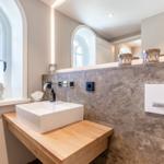 Bathroom with sink on wooden vanity, stone wall, and mirror