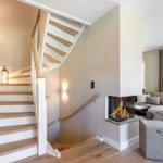 Staircase with wooden steps and handrail, fireplace, and living area with sofa and window.