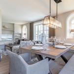 Dining area with wooden table, bench, and modern pendant light. Living area with fireplace in background.