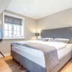 Bedroom with double bed, window, and TV on stand.