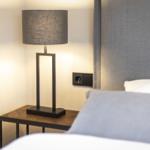 Bedroom with nightstand, lamp, and gray headboard.