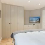 Bedroom with bed, wardrobe, and TV mounted on the wall.