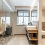 Bathroom with shower, sink, and toilet. Wooden vanity and glass partition.