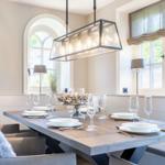 Dining room with long wooden table, chairs, and windows with curtains.