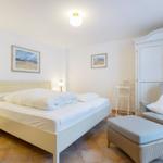 Schlafzimmer mit Bett, Schrank und Sessel. Wandbilder und Steintile.