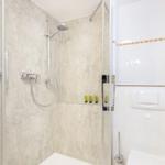 Dusche mit Duschbrause und Toilette im Badezimmer