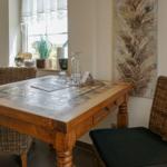 Dining room with wooden table, wicker chairs, and window view.
