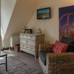 Living room with armchair, dresser, and TV. Window to terrace.