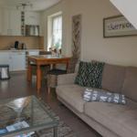 Living room with sofa, glass table, and view into the kitchen