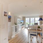 Dining area with table and chairs, living area with TV and window to terrace.