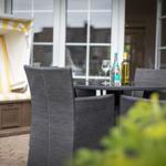 Terrace with dining table, chairs, and beach cabana with yellow-white stripes.