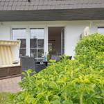 Terrace with beach chair, table and chairs. Backyard with green shrubs.