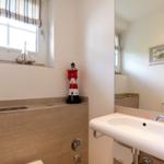 Bathroom with sink, mirror, window, and red lighthouse model.