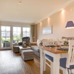 Living and dining area with hardwood floor, TV, table with chairs, and balcony view.