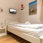 A bedroom with a white bed, nightstand, and wall-mounted TV.