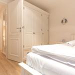 Bedroom with white bed, wardrobe, and TV on the wall.