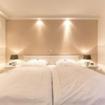 Double bed with white bedding, nightstands with lamps and wall art