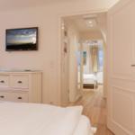Bedroom with TV and view into adjacent room.